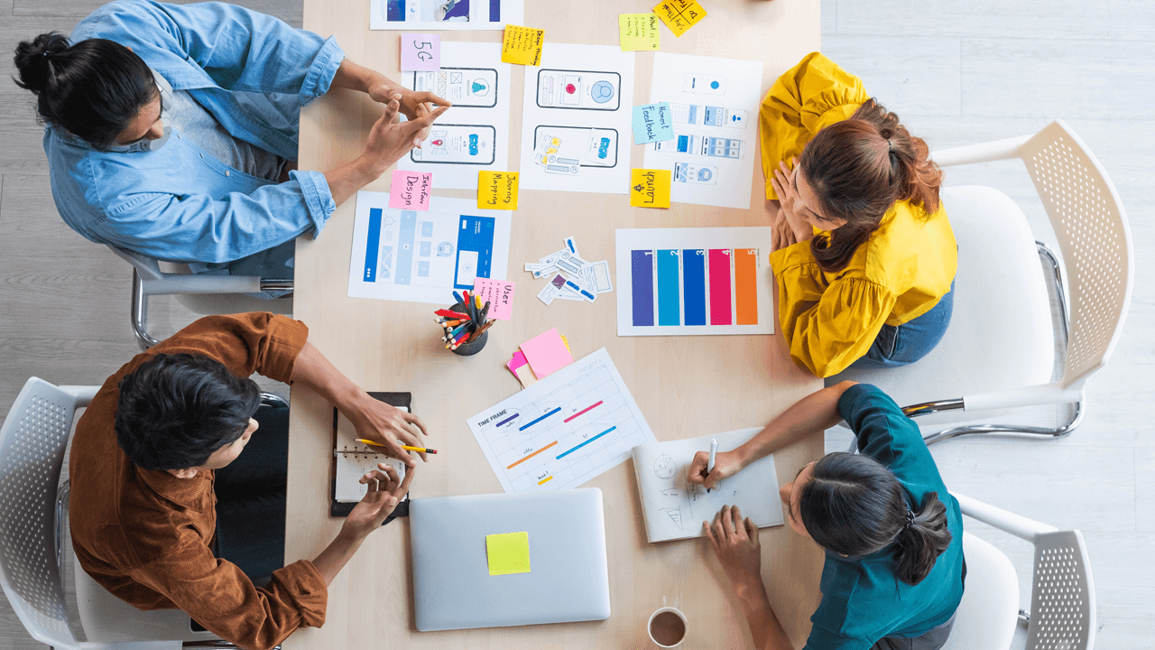 Four people around a table looking at charts and data