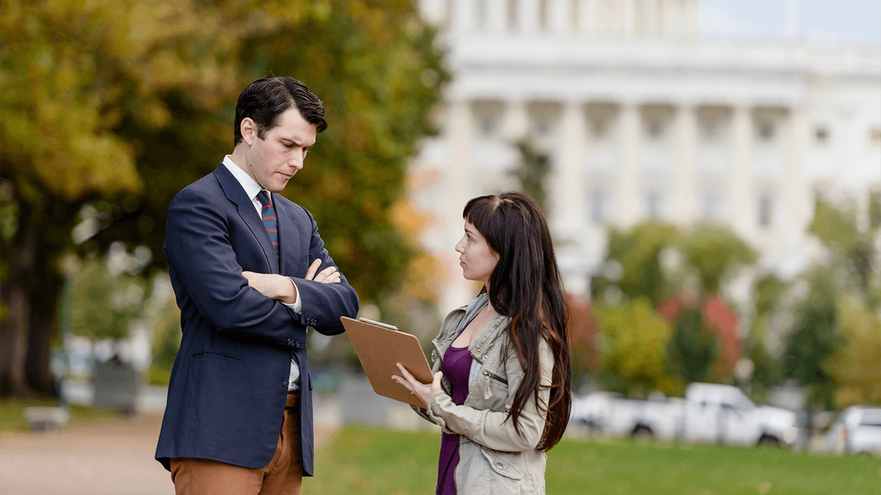 Female reporter questions man outdoors in Washington