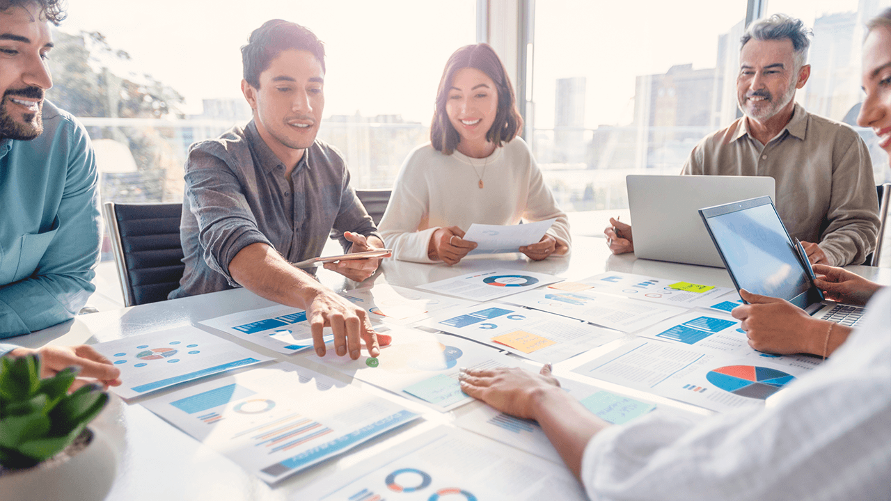 Four people around a table looking at charts and data